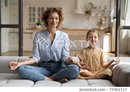 Calm young mom and small daughter practice yoga 75962117