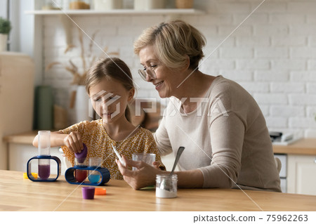 Mature grandmother and little granddaughter play with toy lab 75962263