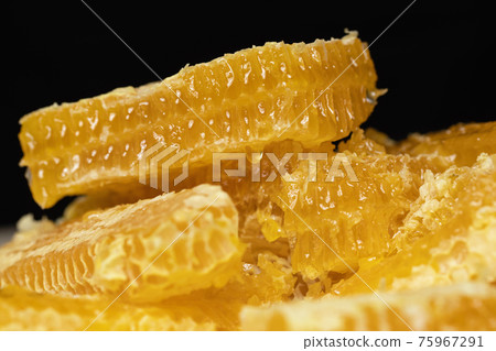 Yellow honey comb slice with fresh honey on black background. Yellow honey comb slice with fresh honey on black background. 75967291
