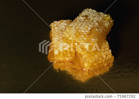 Yellow honey comb slice with fresh honey on golden background Yellow honey comb slice with fresh honey on golden background 75967292