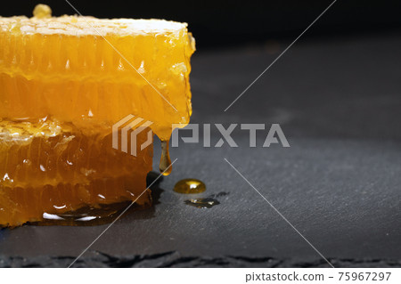 honey dripping from pieces of cut honeycomb 75967297