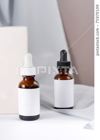 Pipette with drop of cosmetic oil above brown bottle with box 75970109