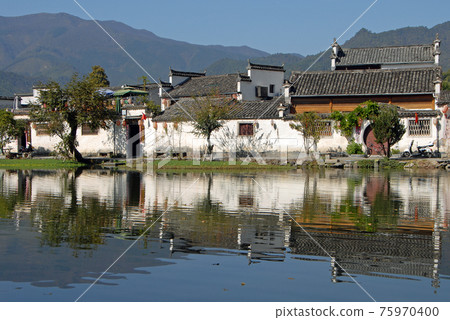 Hongcun Ancient Town in Anhui Province, China. A beautiful view of the old buildings of Hongcun with their reflection in the water of Nanhu Lake. The pretty, ancient town of Hongcun in China. 75970400
