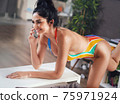 Fit brunette lady doing exercises and talking on the phone 75971924