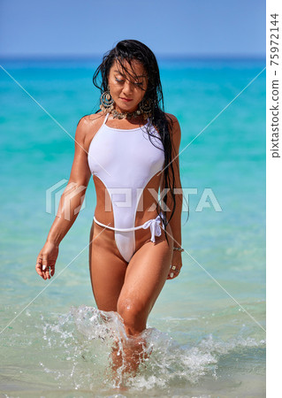 Sexy girl in a white swimsuit walking at the tropical beach 75972144