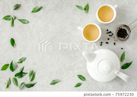 Herbal tea with two white tea cups and teapot, with green tea leaves. Flat lay, top view. Tea concept 75972230