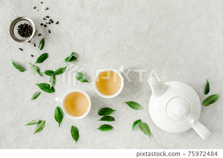 Herbal tea with two white tea cups and teapot, with green tea leaves. Flat lay, top view. Tea concept 75972484