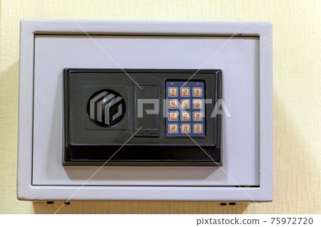A small safe with a dial is mounted on the wall. 75972720
