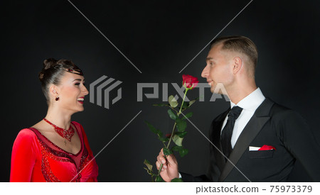 Happy woman in red dress and man with rose flower Happy woman in red dress and man with rose flower 75973379