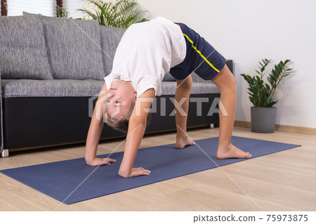 Blond boy goes in for sports on yoga mat. Child physical activity at home. Sport healthy lifestyle active leisure 75973875