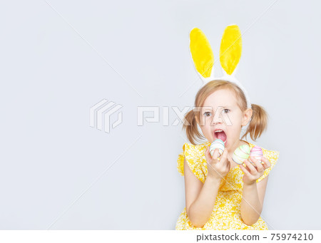 Little Caucasian girl posing on plain background in yellow dress and bunny ears Little Caucasian girl posing on plain background in yellow dress and bunny ears 75974210