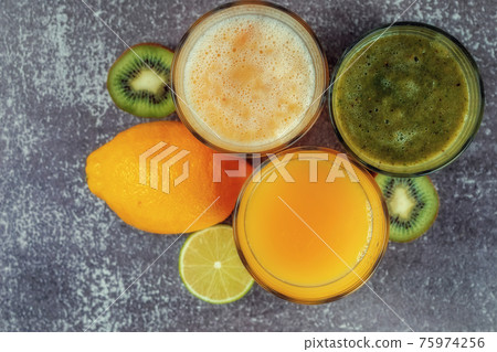 Top view of glasses of orange juice and banana kiwi and spinach smoothies 75974256