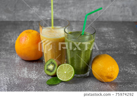 Two tall glasses of orange juice and a banana-orange kiwi and spinach smoothie 75974292