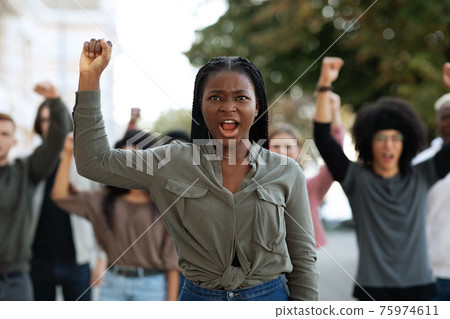 Black woman raising fist up, leading international group of demonstrators Black woman raising fist up, leading international group of demonstrators 75974611