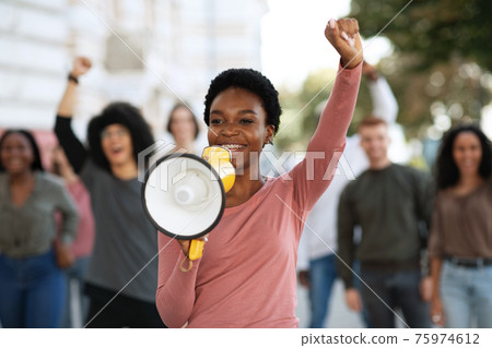 Female leader of strikers with loudspeaker yelling demands to government 75974612