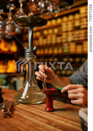 Hookah maker prepares hooka for smoking in bar Hookah maker prepares hooka for smoking in bar 75975168