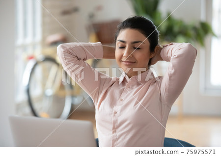Calm Indian female employee relax at workplace Calm Indian female employee relax at workplace 75975571