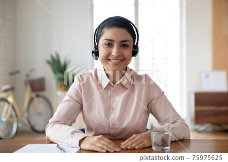 Portrait of Indian woman in headset talk on video call 75975625