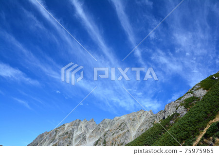 The ridgeline of the hanging ridge between Mt. Shinshu Northern Alps and Mt. Maehotaka, high pine, blue sky, summer sky, and wavy cirrus clouds. Streak clouds. 75975965