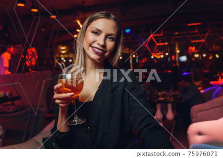 Young woman sipping red sweet drink in bar. Young woman sipping red sweet drink in bar. 75976071