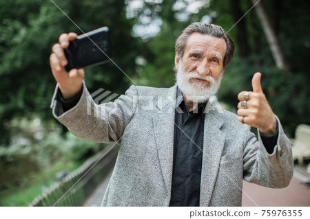 Mature man showing thumb up while taking selfie 75976355