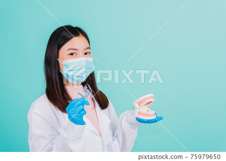 woman dentist holding silicone orthodontic retainers and model teeth denture 75979650