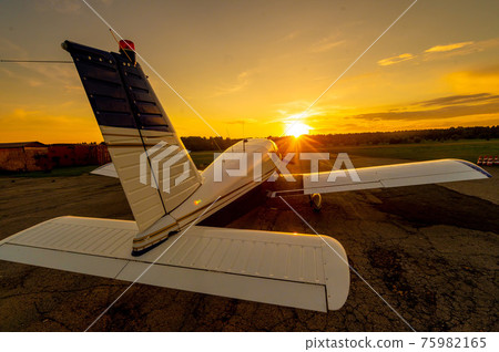 Quadruple aircraft parked at a private airfield. Rear view of a plane with a propeller on a sunset background. 75982165