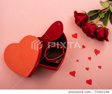 Bdsm set in a box in the form of a heart and red roses on a pink background. Valentine's day gift idea 75982246