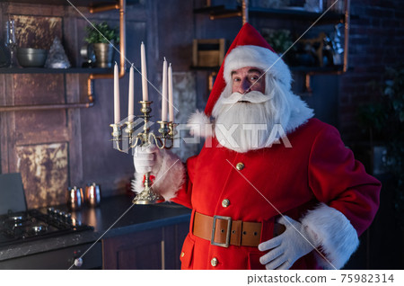 Santa claus sneaks up at night and holding a candelabrum. Santa claus sneaks up at night and holding a candelabrum. 75982314