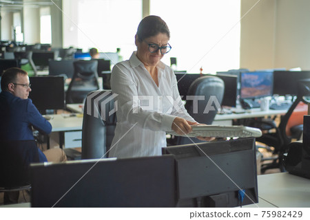 A woman freaks out and gets depressed from a mistake and breaks the keyboard on the monitor. Female manager gets angry and crashes a computer. Office clerk is stressed at work. Unstable psyche. 75982429