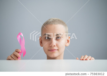 Young woman with pink ribbon on a white background. Mammary cancer 75983012