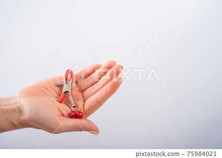 Close up nipple clamps in a female hand on a white background. BDSM sex toy Close up nipple clamps in a female hand on a white background. BDSM sex toy 75984021