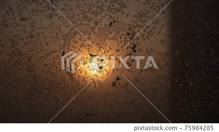 A heart drawn on a frozen winter window at sunset. A heart drawn on a frozen winter window at sunset. 75984285