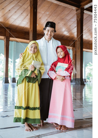 Portrait of an Muslim teacher and Muslim children holding the al quran book Portrait of an Muslim teacher and Muslim children holding the al quran book 75984443