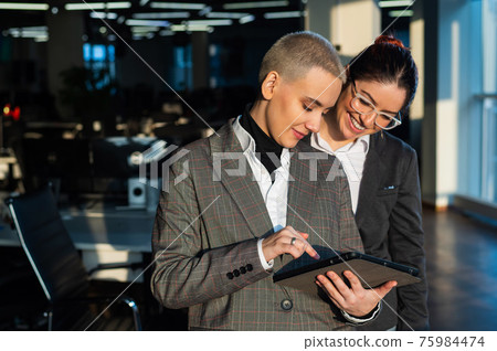 Two young business women looking at digital tablet in office. 75984474