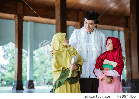 Portrait of an Muslim teacher and Muslim children holding the al quran book stare at each other 75984490