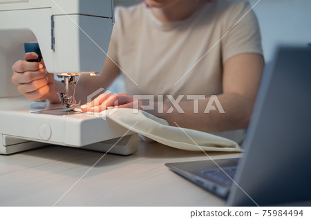 Close-up. A woman works on an electric sewing machine at home Close-up. A woman works on an electric sewing machine at home 75984494