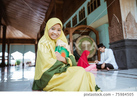 asian girl muslim smiling holding al quran book and learning to read quran with muslim teacher aur ustad 75984505