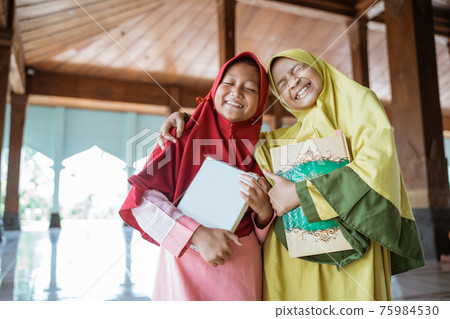 kids woman asia Muslim laugh holding al quran book and hug each other 75984530