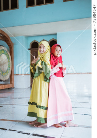 Kids woman Muslim pose and show thumbs looking at cameras 75984547