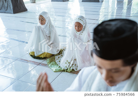 Portrait Asian Muslim male teacher and two girls praying jamaah together Portrait Asian Muslim male teacher and two girls praying jamaah together 75984566