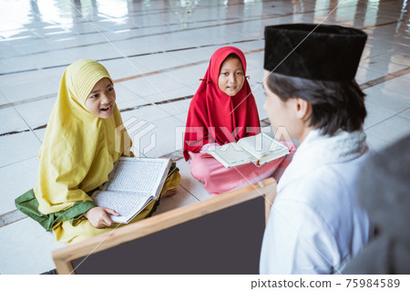 two kids learning to read quran with muslim teacher or ustad two kids learning to read quran with muslim teacher or ustad 75984589