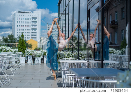A beautiful ballerina is dancing outdoors on a warm summer day. Young flexible woman in pointe shoes and ballet tutu posing in a street cafe A beautiful ballerina is dancing outdoors on a warm summer day. Young flexible woman in pointe shoes and ballet tutu posing in a street cafe 75985464