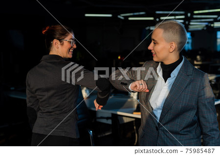 Two Caucasian business women greet each other in the office. Social distance at work 75985487