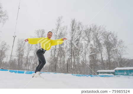 Professional skater on an outdoor ice rink. A woman on knees is preparing a solo program for the competition. 75985524
