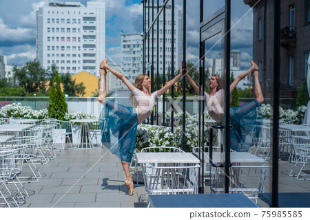 A beautiful ballerina is dancing outdoors on a warm summer day. Young flexible woman in pointe shoes and ballet tutu posing in a street cafe A beautiful ballerina is dancing outdoors on a warm summer day. Young flexible woman in pointe shoes and ballet tutu posing in a street cafe 75985585
