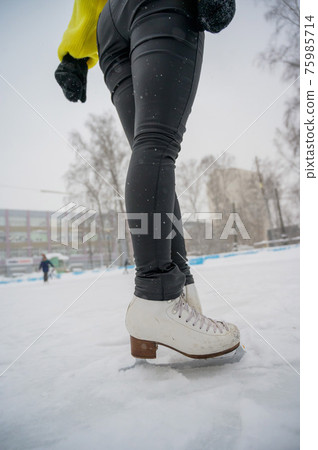 Figure skating on the street at an outdoor ice rink. Close-up of the skater's legs on ice. A woman goes in for sports. Figure skating on the street at an outdoor ice rink. Close-up of the skater's legs on ice. A woman goes in for sports. 75985714