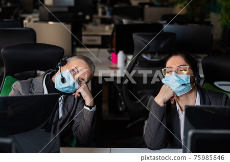 Two women in protective masks are bored at work. Call center operators at the desk 75985846
