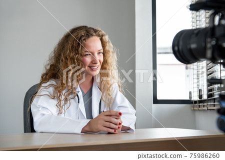 Smiling cheerful Caucasian woman doctor doing live streaming from hospital 75986260