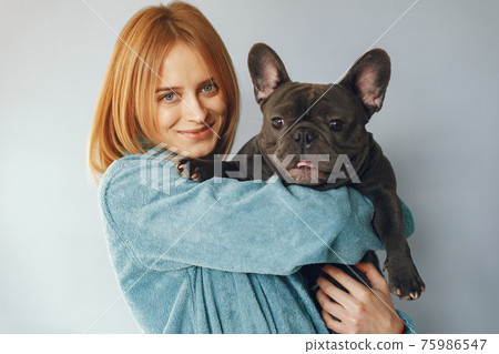 Elegant woman in a blue bathrobe with black bulldog Elegant woman in a blue bathrobe with black bulldog 75986547